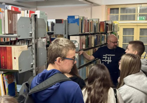 Czwórka uczniów przy regałach bibliotecznych