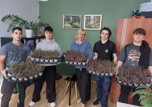 Uczniowie z Dyrekcją pozują do zdjęcia z otrzymanymi wrzosami