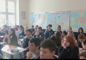 Uczniowie siedzący na tle map