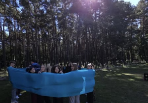 Uczniowie w kręgu owinięci szerokim materiałem