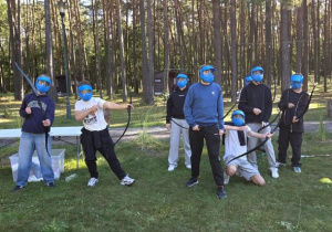 Chłopcy stojący z łukami w ręku i maskami na twarzy