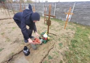 Uczeń pochylający się nad grobem