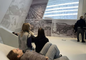 Uczniowie w słuchawkach siedzący przed wyświetlaną prezentacją