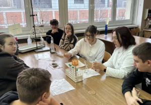 Uczniowie siedzący przy stole i robiący doświadczenie