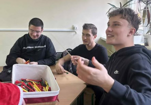 Siedzący chłopiec wyciąga długopis z koszyka