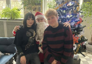 Chłopiec i dziewczynka na kolanach Mikołaja na tle choinki