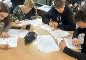 Czwórka uczniów przy stole piszący listy