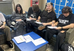 Grupa uczniów na tel szafek szkolnych podczas pisania listów