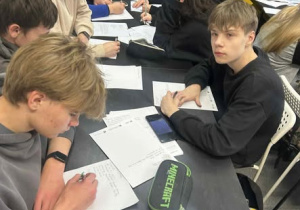 Uczniowie przy stołach piszący listy