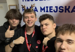 Czterech uczniów na tle baneru