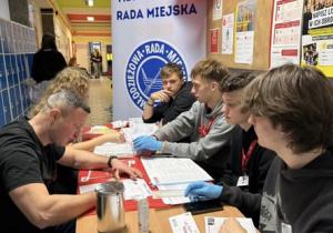 Uczniowie przy stoliku z materiałami informacyjnymi