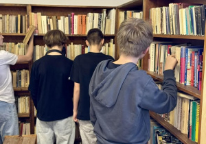 Chłopcy przy regałach z książkami