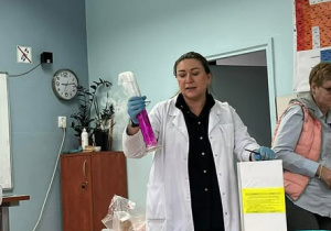 Nauczycielka w białym fartuchu z probówką w ręku