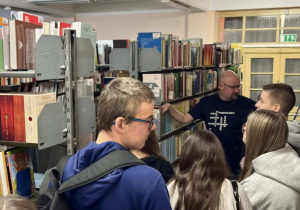 Czwórka uczniów przy regałach bibliotecznych