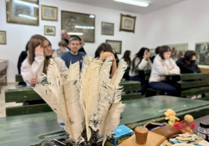 Uczniowie w dawnej klasie na tle piór gęsich