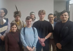 Uczniowie stojący w towarzystwie Panów w strojach szlacheckich