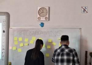 Studenci przodem do tablicy z karteczkami