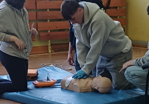 uczeń uciska fantoma a obok uczennica podłącza AEG